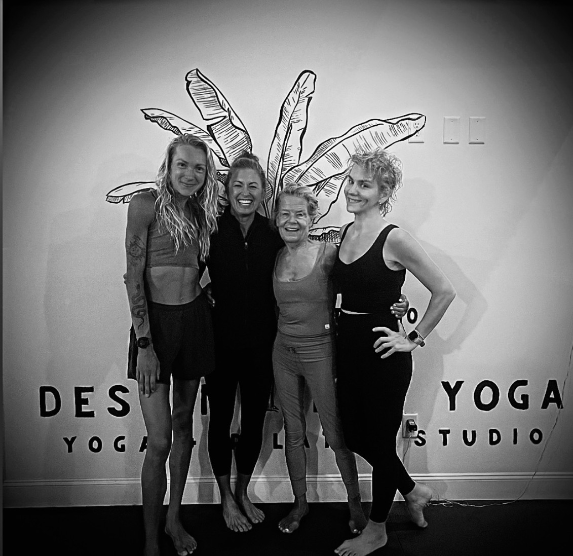 Megan Baye and Destin Hot Yoga + Pilates instructors in front of the studio mural